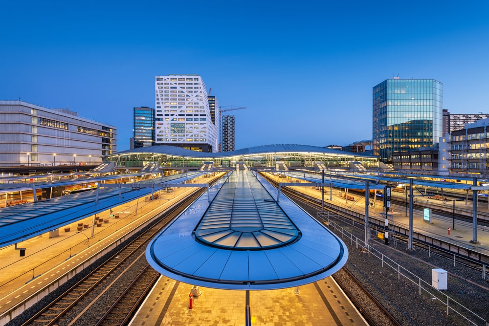 Utrecht, Netherlands cityscape over train station platforms at dawn.